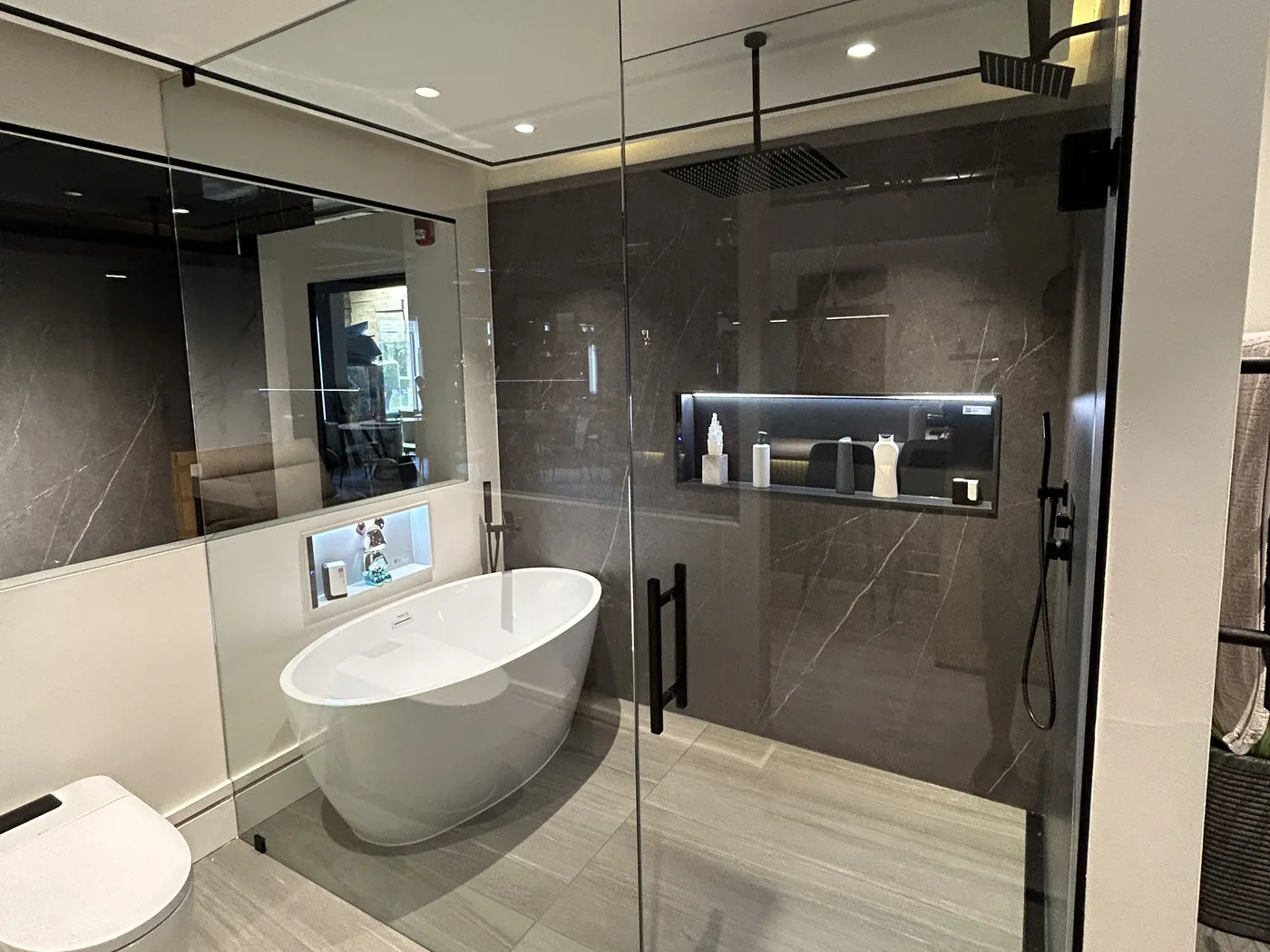Primary bathroom with a freestanding soaking tub, a frameless glass shower and a lit tile niche