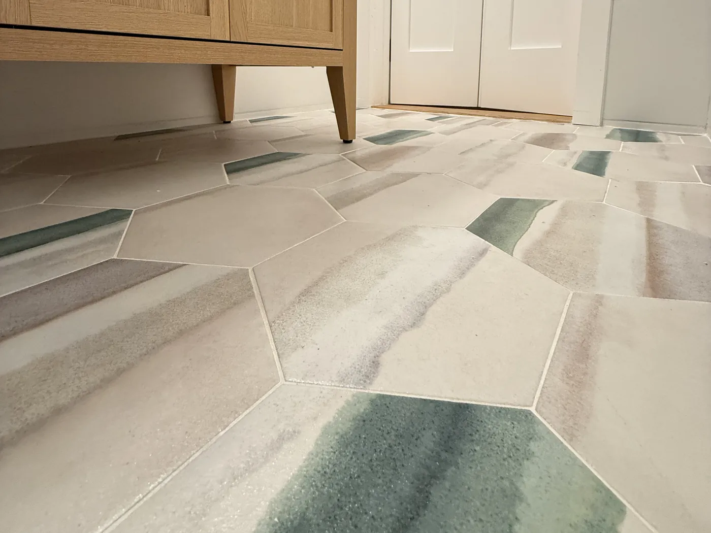 Large hexagon tile floor with green and gray veining laid through a bathroom