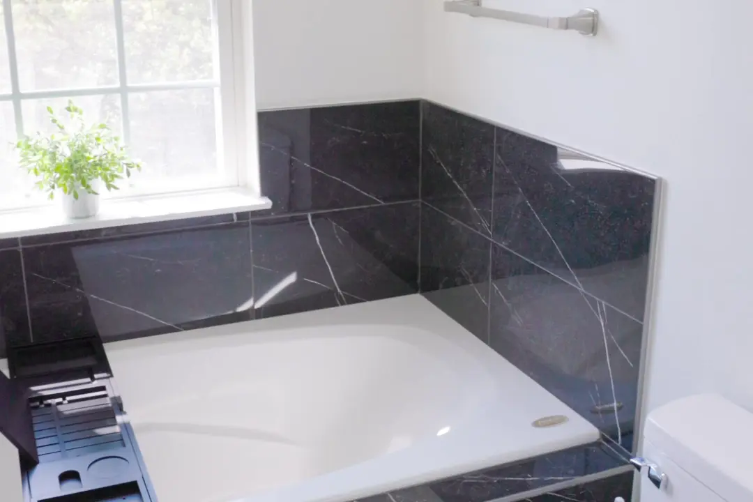 Soaking tub set into a black marble surround under a window