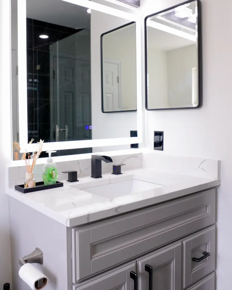 Double vanity with a quartz top, matte black faucets and backlit mirrors